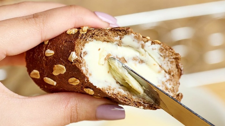 buttering a slice of Cheesecake Factory's brown bread loaf