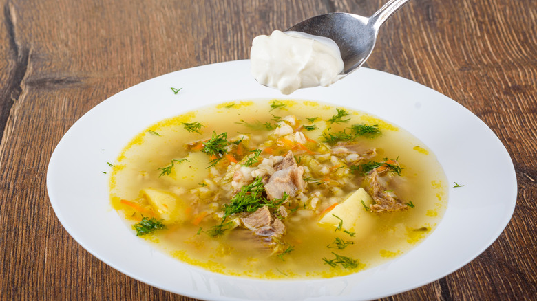 putting a spoonful of sour cream in a bowl of soup