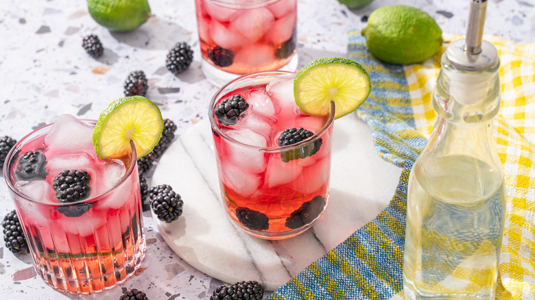 Pink berry mocktails beside limes and blackberries