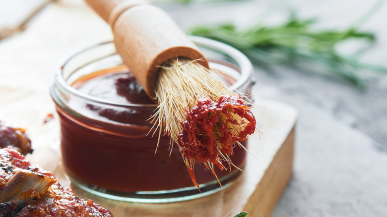 A basting brush balancing on top of a small bowl of barbecue sauce