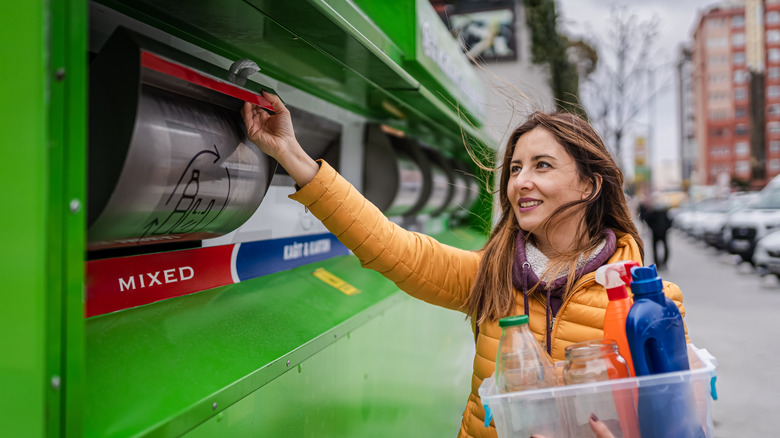 A woman placing recyclable items in a collection bin labeled 'mixed' at a recycling facility