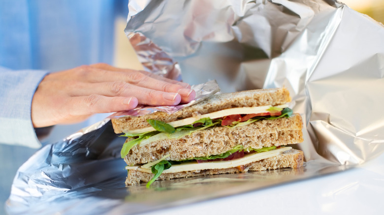 Woman wraps sandwich in aluminum foil