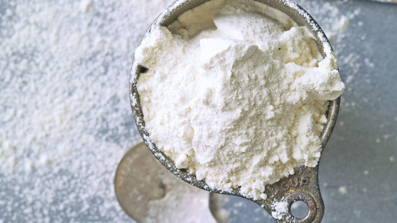 flour in measuring cup and on counter with spoon and knife