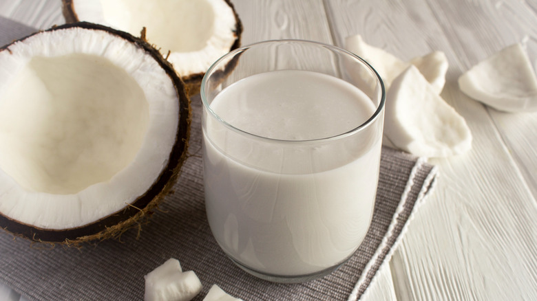 A split coconut and cup of coconut milk