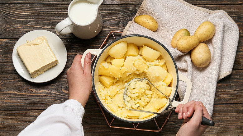 Person mashing potatoes in pot