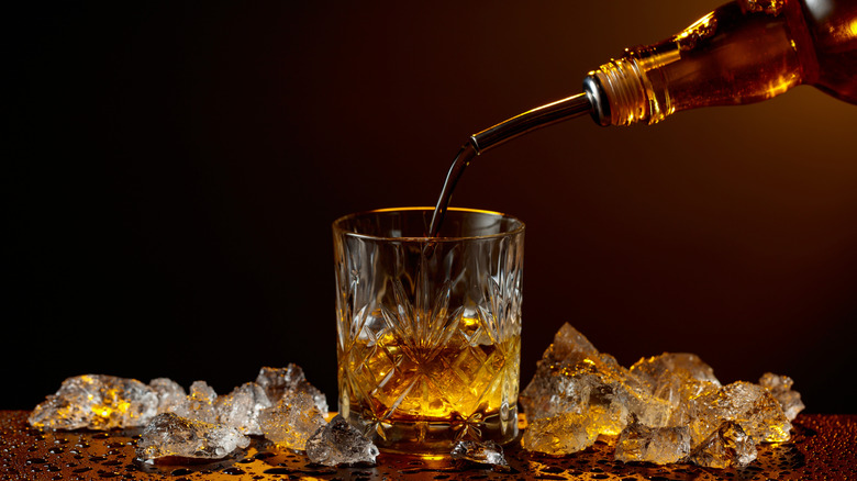 Bottle pouring whiskey into glass.