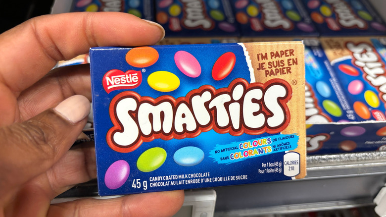 Hand holding a box of Nestlé Smarties in a store
