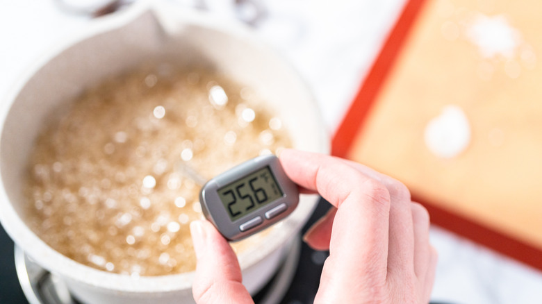 Overhead view of candy thermometer over saucepan of caramel
