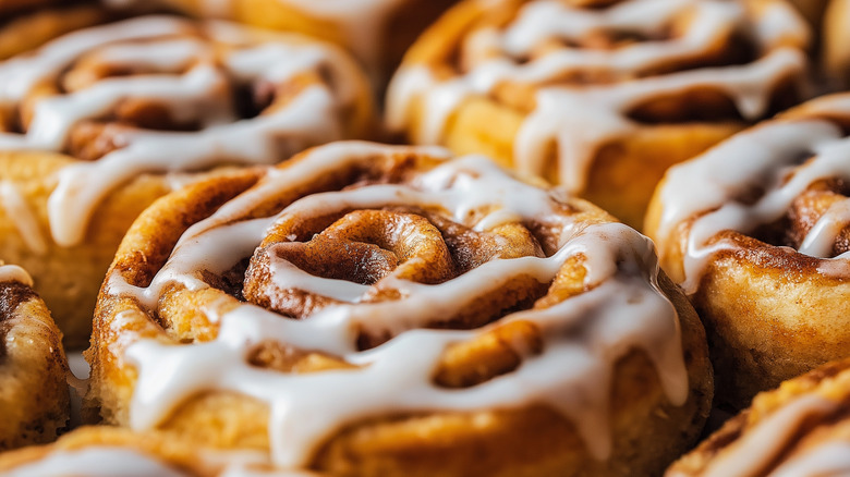 Close-up of baked cinnamon rolls drizzled with cream cheese icing