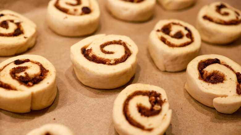 Overhead view of raw cinnamon rolls on a lined pan.