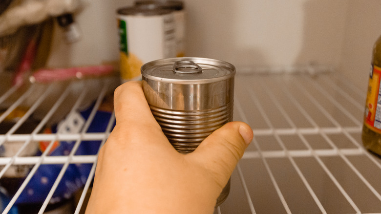 person grabbing can from pantry