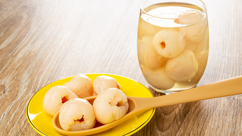 glass of canned lychees in syrup with bowl of lychees