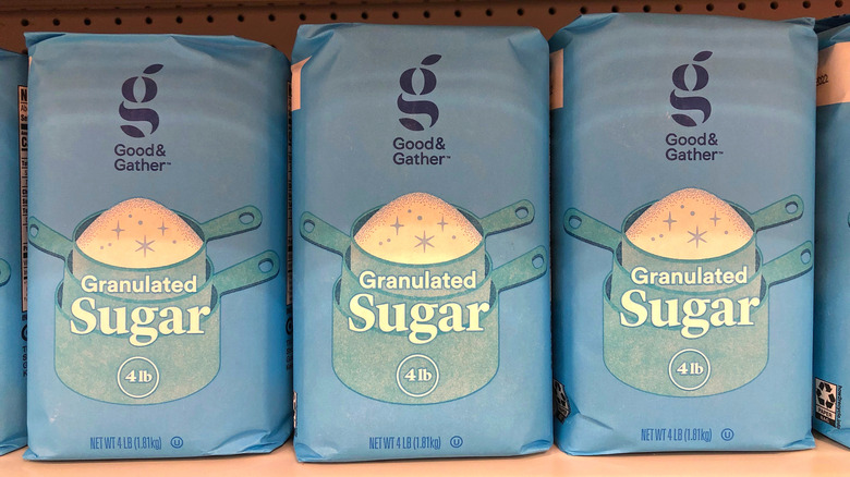 Three light blue, 4-pounds bags of Good & Gather brand granulated sugar on a store shelf