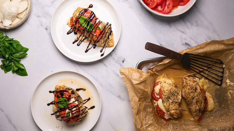 Two Caprese-stuffed chicken breasts on two white plates