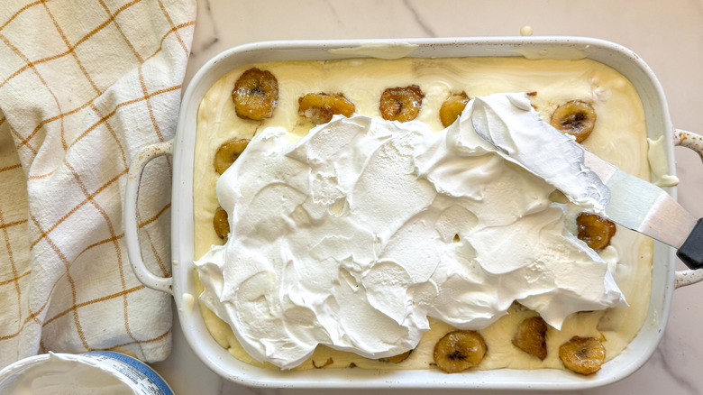 spreading whipped topping on banana pudding cake