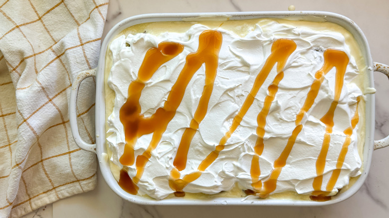 Cake topped with whipped topping and caramel drizzle