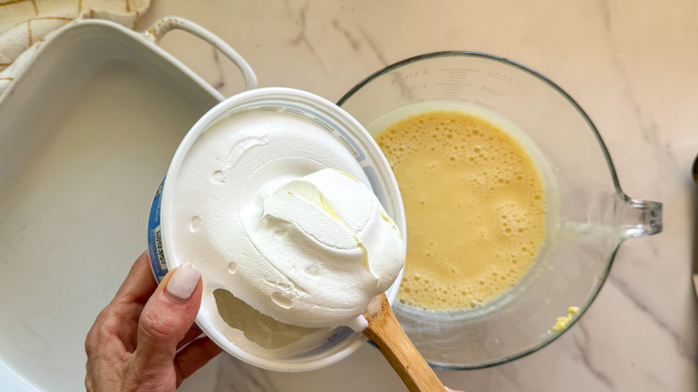 hand adding whipped topping to pudding