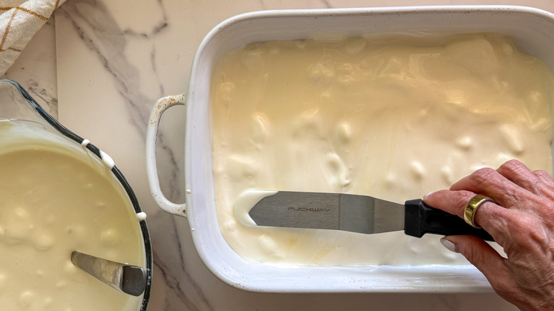 hand spreading pudding in baking dish