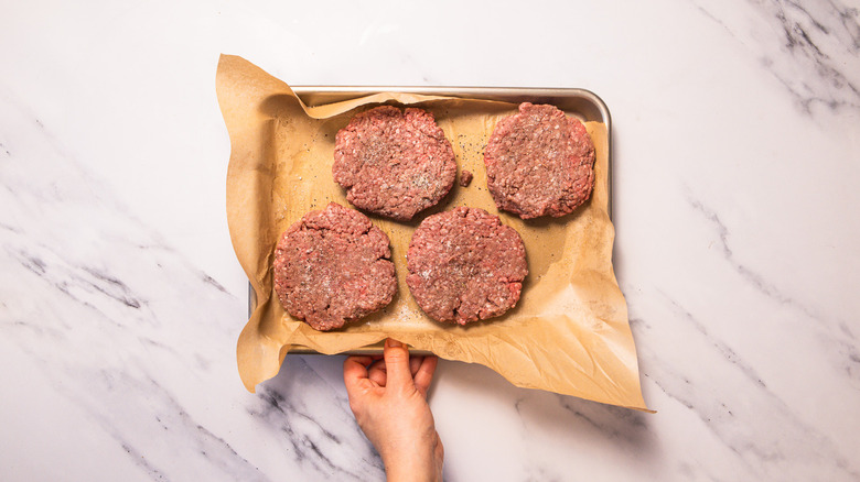 Uncooked burger patties on baking sheet