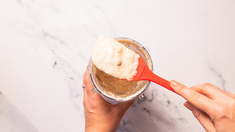 Blended apple mayonnaise in jar lifted out with a spatula