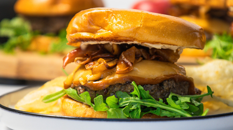 Close up side view of a caramelized apple burger on a plate