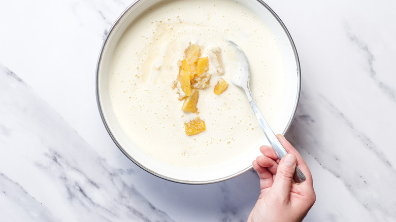 Adding pineapple to custard in bowl