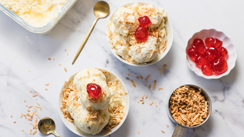 Two pineapple ice creams with maraschino cherries and toppings