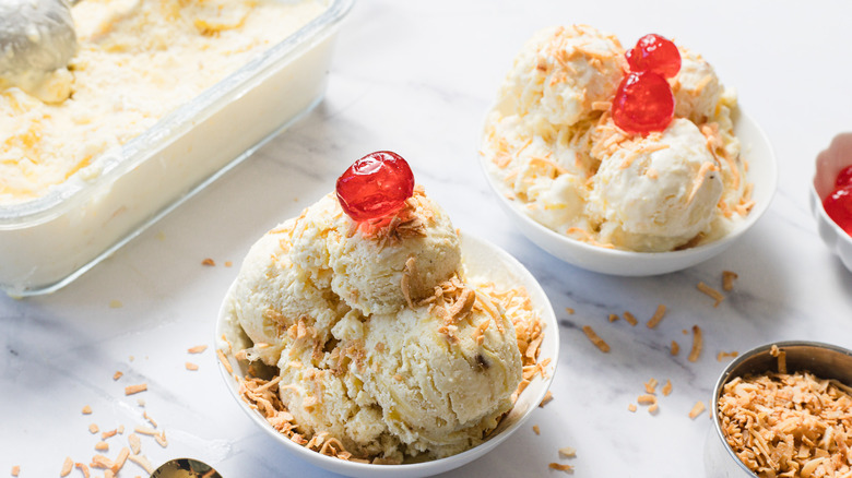 Two pineapple ice creams with maraschino cherries and spoons