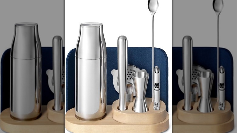 Silver shaker and cocktail equipment on a wooden organizer.
