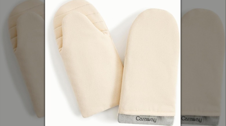 A pair of cream-colored oven mitts on a white background.
