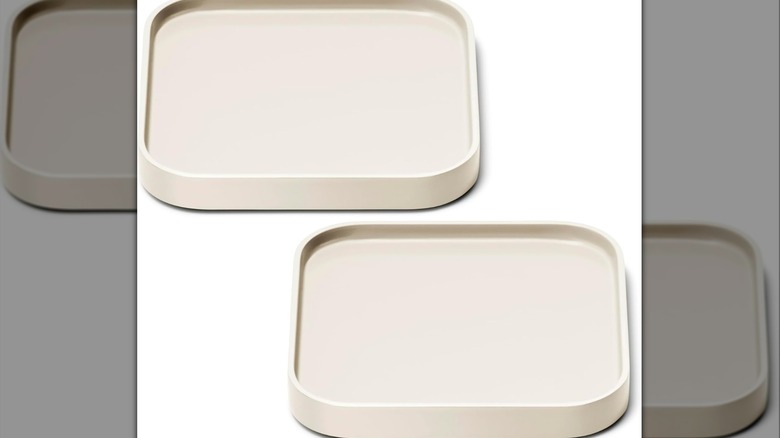 Set of two cream-colored spoon rests on a white background.