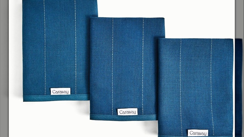 Three blue tea towels with white stripes on a white background.