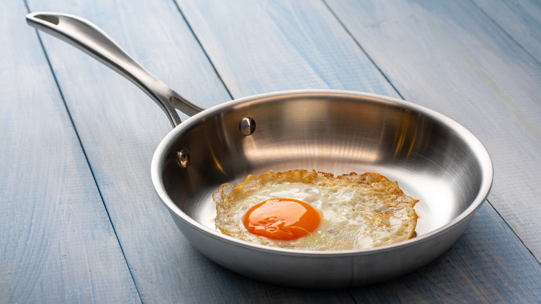 A stainless steel skillet with a fried egg inside.