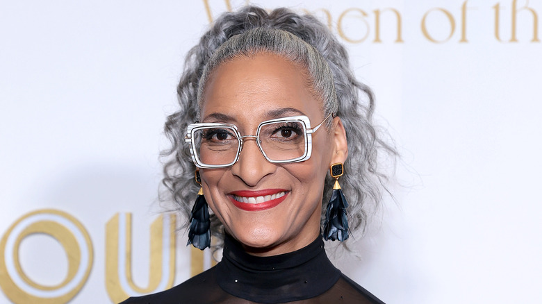 Carla Hall smiling with glasses, red lipstick