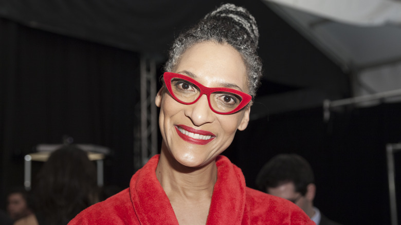 Carla Hall smiling with red glasses and red robe