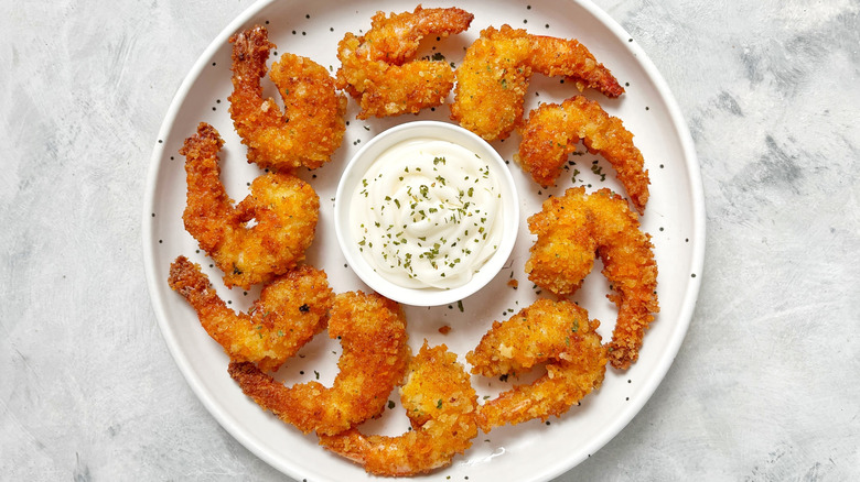 Crispy fried shrimp with tails on surrounding a white dip in a circle