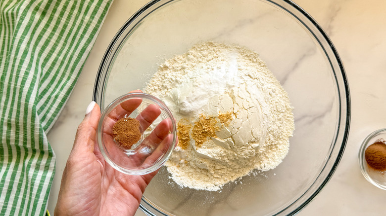 hand adding spice to bowl