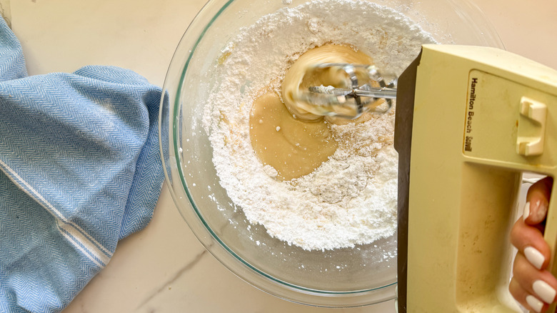 hand using beater on frosting