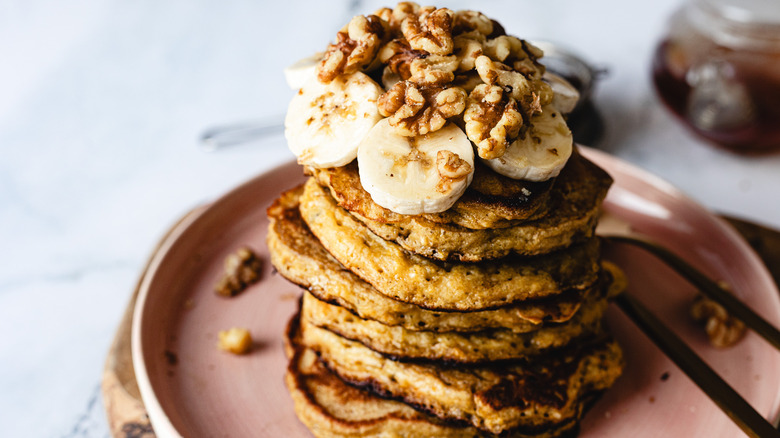 Stack of pancakes with bananas and walnuts on plate