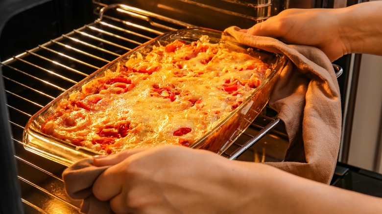 person taking casserole out of oven