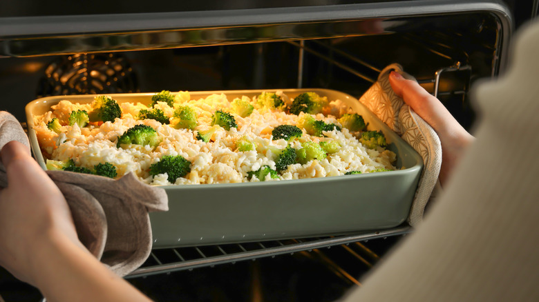 Person placing a casserole in an oven