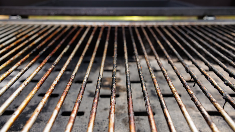 A close-up of a used stainless steel grill grate with grease on it