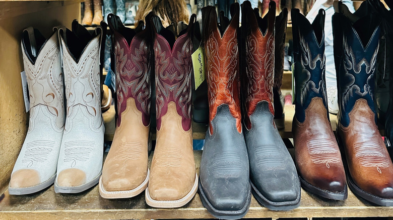 A shelf holds several pairs of cowboy boots.