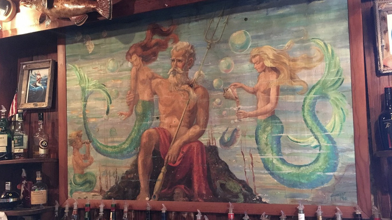 Neptune Lounge Bar Cedar Key mural with Neptune and two mermaids alongside other decor.