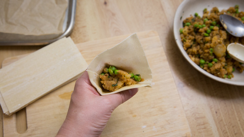 hand holding opened uncooked samosa