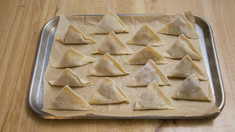 unbaked samosas on baking sheet