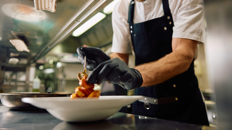 A chef plating up a dish in a restaurant kitchen