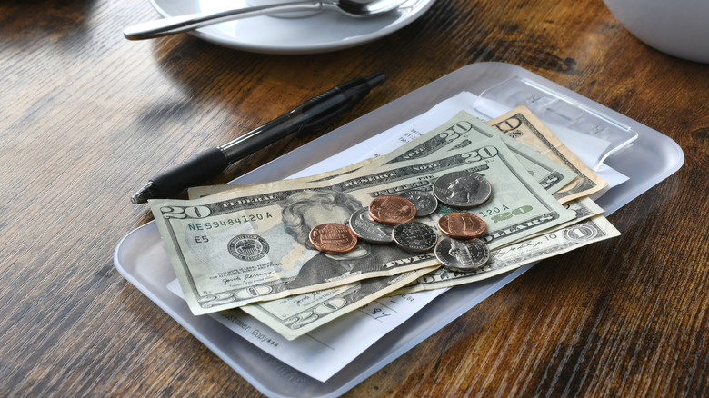 A close-up of some U.S. cash and coin change on a restaurant receipt