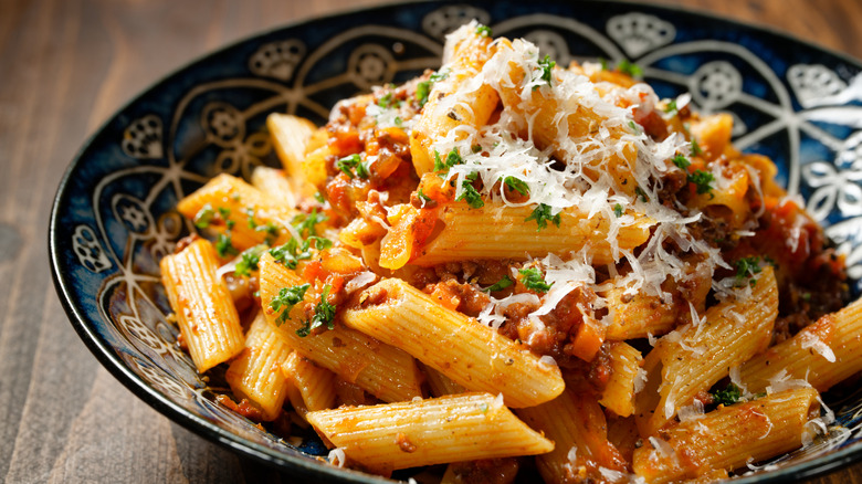 Plate of penne with Bolognese sauce topped with grated cheese and parsley