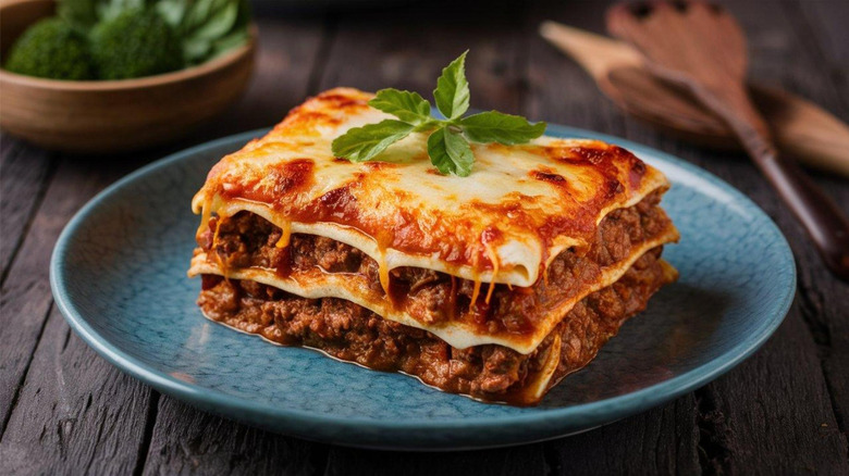 Blue plate with a lasagna slice topped with cheese and garnished with greens